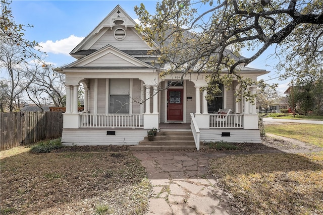 victorian-style house featuring fence and covered porch