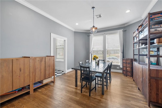 dining area featuring crown molding, wood finished floors, visible vents, and a healthy amount of sunlight