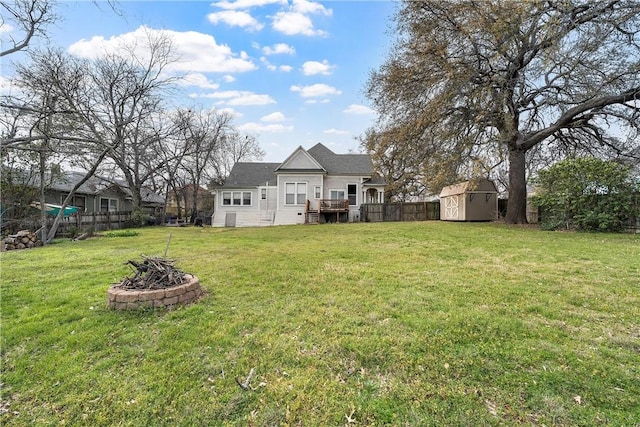 view of yard featuring fence, a fire pit, an outdoor structure, and a shed