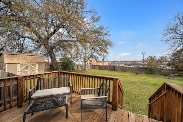 wooden terrace featuring a lawn, an outdoor structure, and a fenced backyard