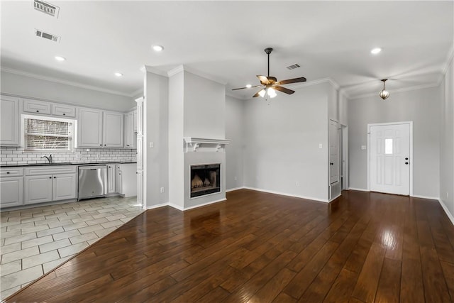 unfurnished living room featuring ceiling fan, sink, crown molding, and light hardwood / wood-style flooring