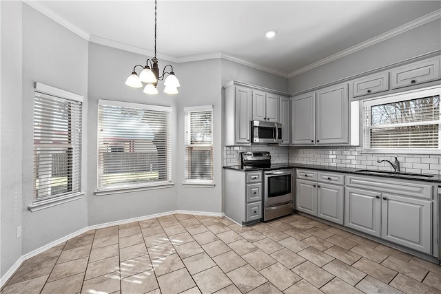 kitchen with gray cabinetry, stainless steel appliances, a healthy amount of sunlight, sink, and a notable chandelier