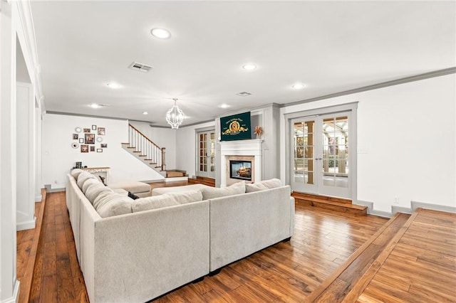 living room featuring hardwood / wood-style flooring, ornamental molding, and a notable chandelier