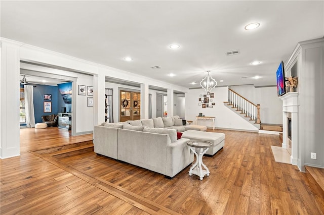 living room with a fireplace, crown molding, light hardwood / wood-style flooring, and a chandelier