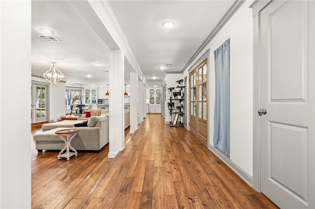 hall featuring crown molding, hardwood / wood-style floors, and a notable chandelier