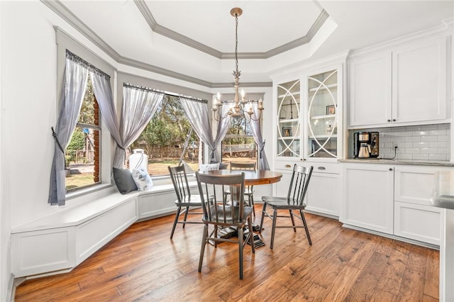 dining area featuring light hardwood / wood-style floors, an inviting chandelier, a tray ceiling, and ornamental molding