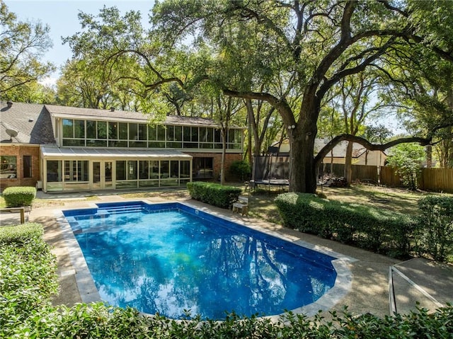 view of swimming pool with a sunroom and a trampoline