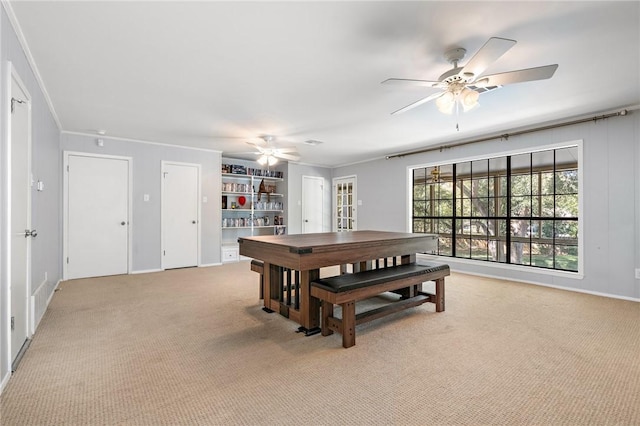 carpeted dining room featuring ceiling fan and crown molding