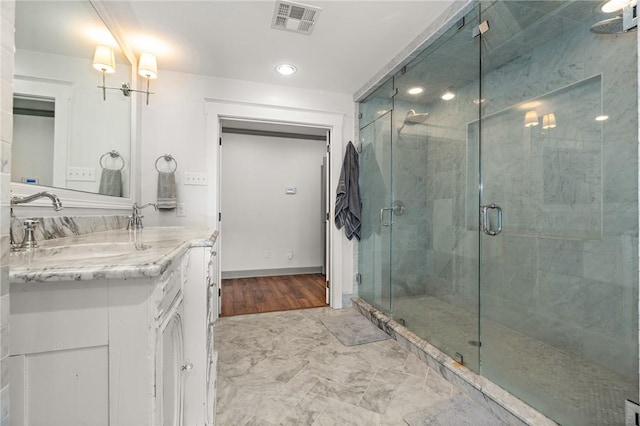 bathroom with hardwood / wood-style floors, vanity, and a shower with door