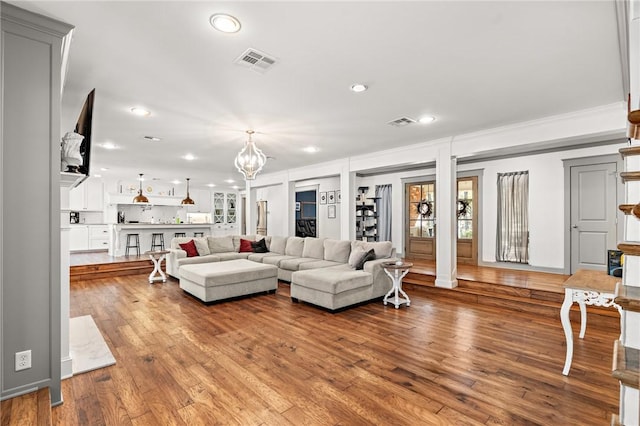 living room with hardwood / wood-style floors, crown molding, and a notable chandelier