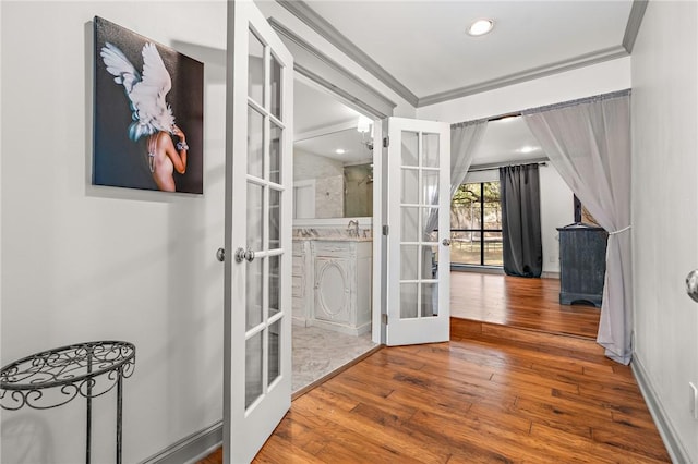 hallway with sink, french doors, wood-type flooring, and ornamental molding