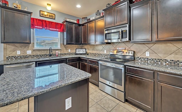 kitchen featuring decorative backsplash, light stone counters, stainless steel appliances, sink, and light tile patterned floors