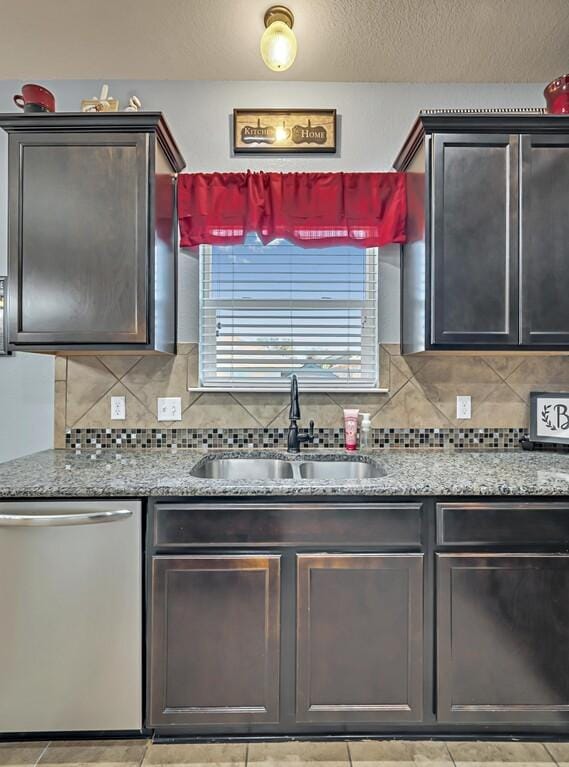 kitchen featuring light stone counters, tasteful backsplash, stainless steel dishwasher, and sink