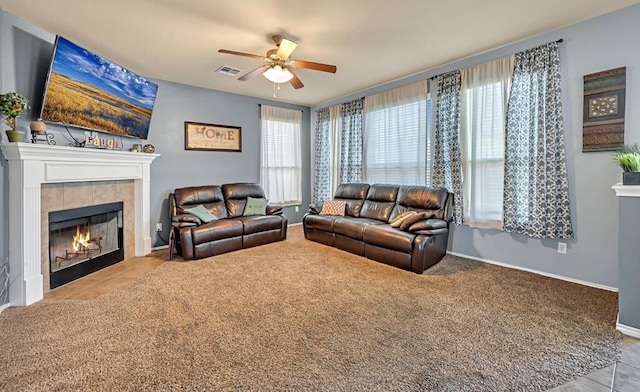 carpeted living room featuring a tiled fireplace and ceiling fan