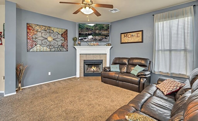 carpeted living room with a tiled fireplace and ceiling fan