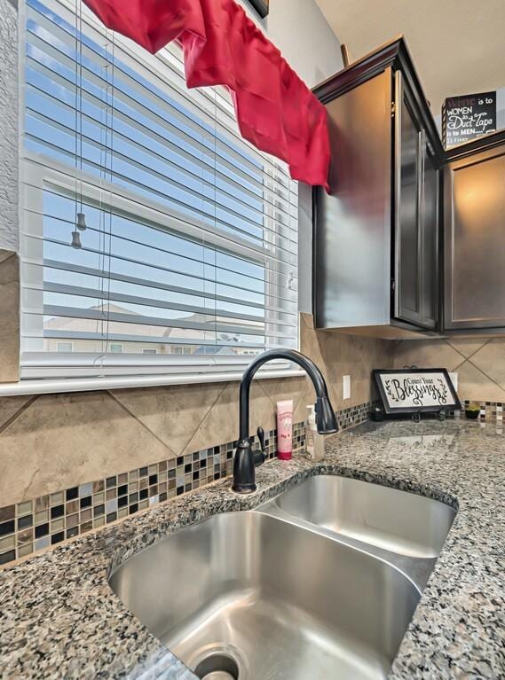 details with backsplash, light stone counters, and sink