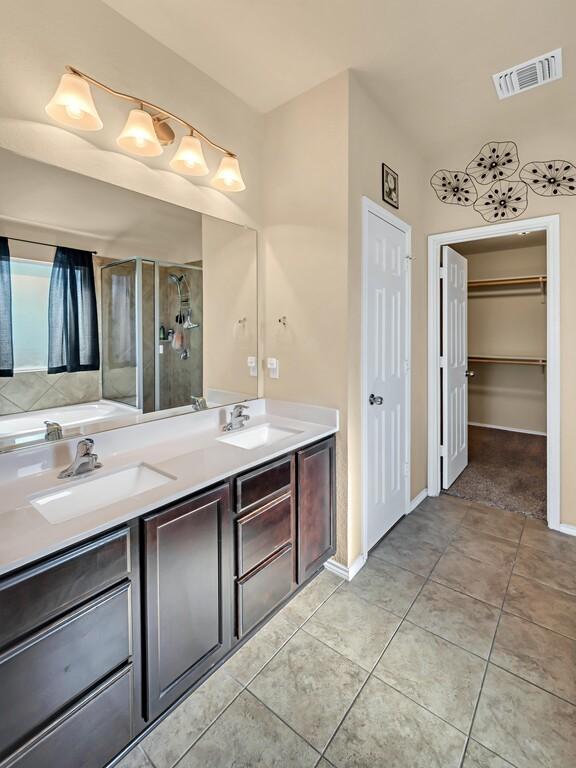 bathroom with tile patterned flooring, vanity, and a shower with shower door