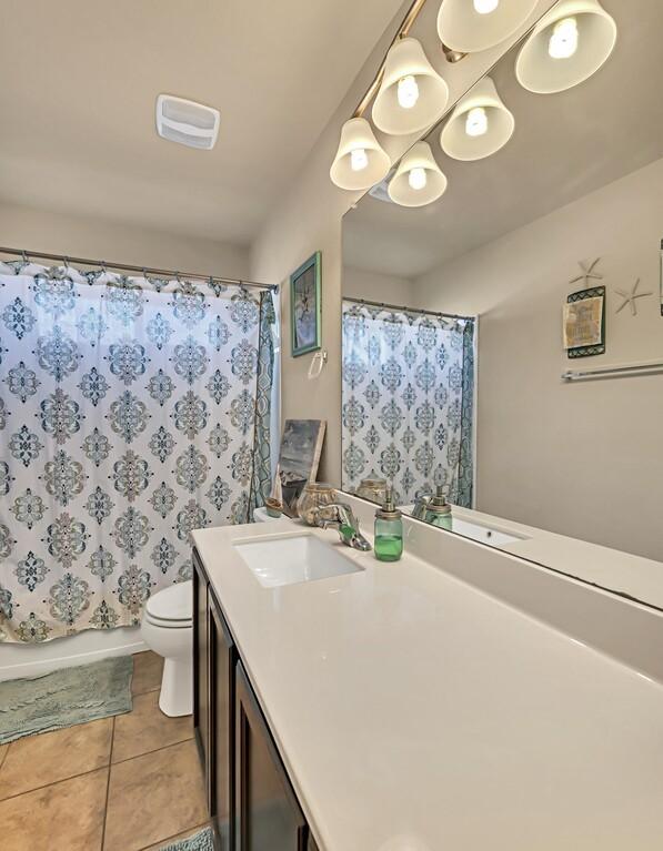 full bathroom featuring tile patterned flooring, vanity, shower / bath combination with curtain, and toilet