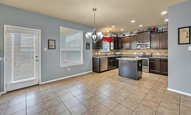 kitchen featuring a healthy amount of sunlight, hanging light fixtures, a kitchen island, and stainless steel appliances