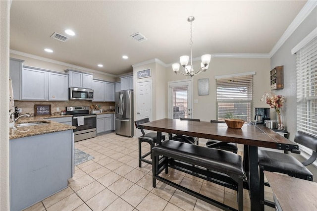 kitchen with gray cabinets, sink, an inviting chandelier, hanging light fixtures, and appliances with stainless steel finishes