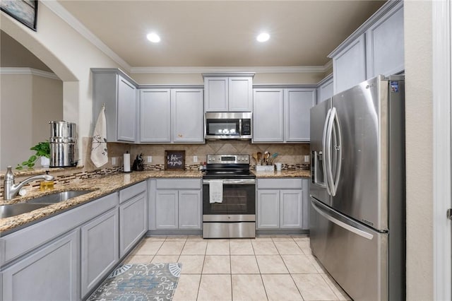 kitchen featuring light stone counters, sink, gray cabinetry, and stainless steel appliances