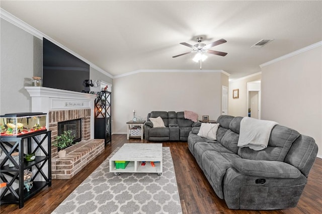 living room featuring ceiling fan, dark wood-type flooring, ornamental molding, and a fireplace