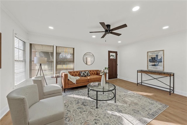 living room featuring light hardwood / wood-style flooring, ceiling fan, and ornamental molding