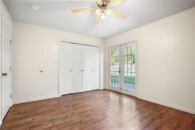 unfurnished bedroom with french doors, a textured ceiling, hardwood / wood-style flooring, and ceiling fan