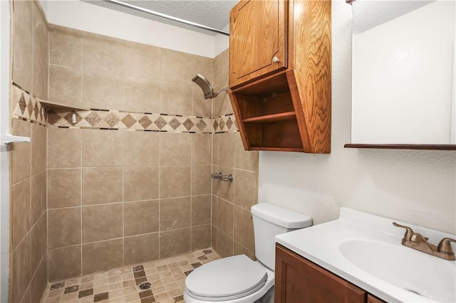 bathroom with vanity, a tile shower, a textured ceiling, and toilet