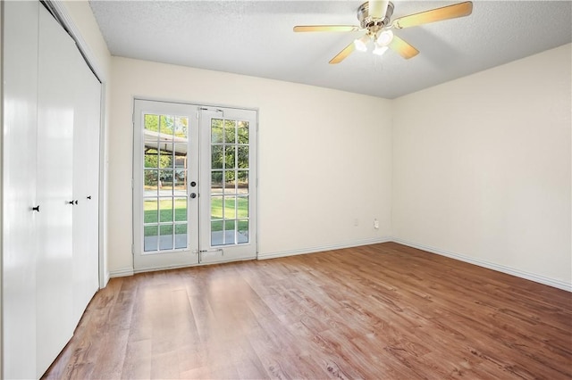 empty room with ceiling fan, french doors, a textured ceiling, and hardwood / wood-style flooring