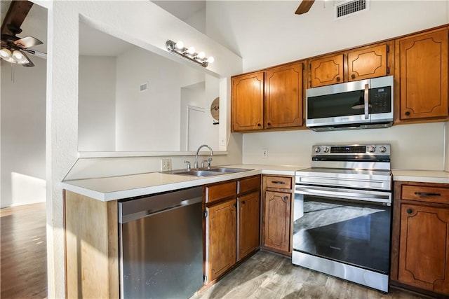 kitchen with sink, vaulted ceiling, hardwood / wood-style flooring, ceiling fan, and stainless steel appliances