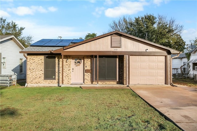 single story home featuring a front yard, solar panels, and a garage