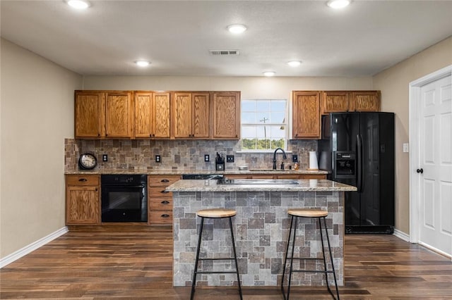 kitchen featuring a kitchen bar, a center island, dark hardwood / wood-style floors, and black appliances