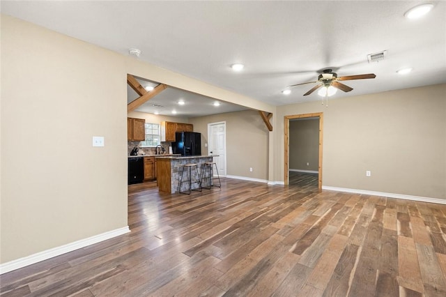 unfurnished living room with ceiling fan, dark wood-type flooring, and sink