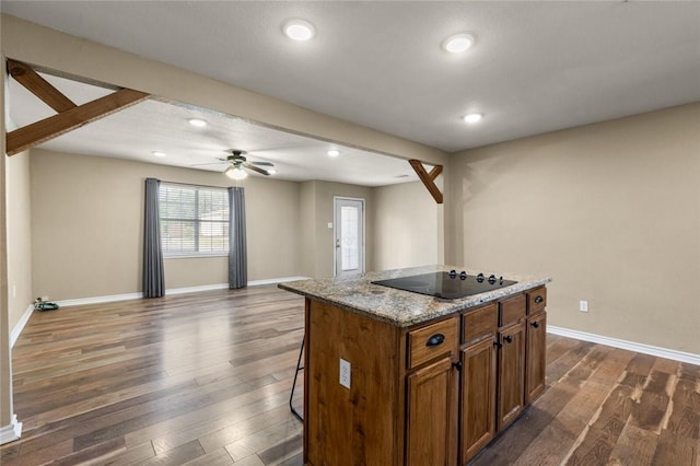 kitchen featuring a kitchen bar, black electric stovetop, a center island, and dark hardwood / wood-style flooring