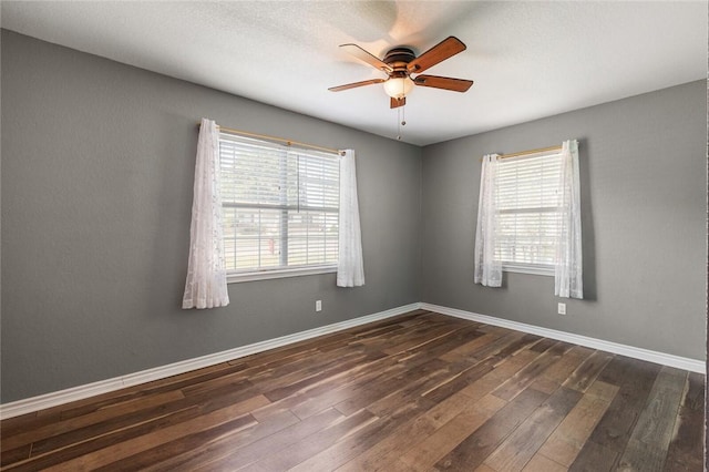 spare room featuring dark hardwood / wood-style floors, ceiling fan, and a healthy amount of sunlight