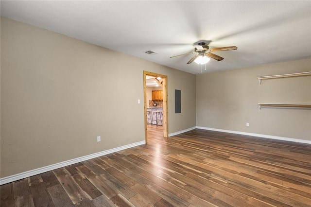 empty room with dark hardwood / wood-style flooring, electric panel, and ceiling fan