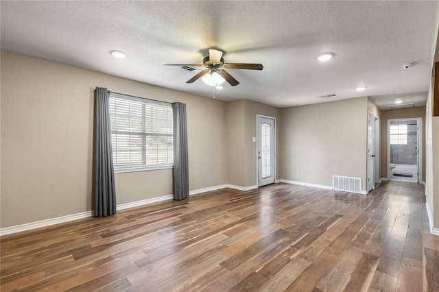 unfurnished room with ceiling fan, dark hardwood / wood-style flooring, and a textured ceiling