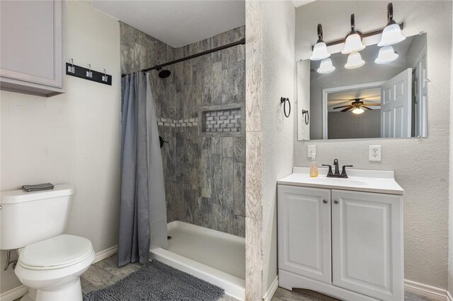 bathroom featuring a shower with curtain, ceiling fan, toilet, and vanity