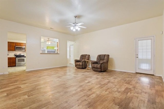 sitting room featuring light wood finished floors, a ceiling fan, and baseboards