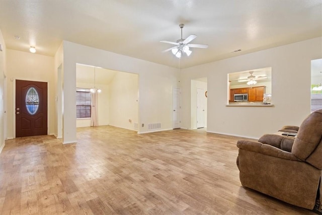 living room featuring ceiling fan with notable chandelier, light wood-type flooring, and visible vents