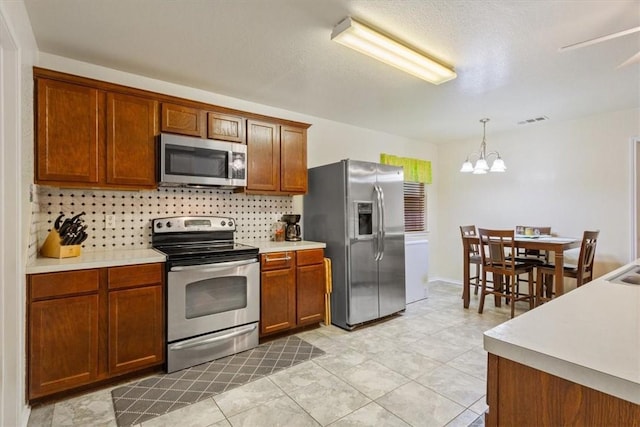 kitchen with stainless steel appliances, tasteful backsplash, light countertops, visible vents, and brown cabinetry