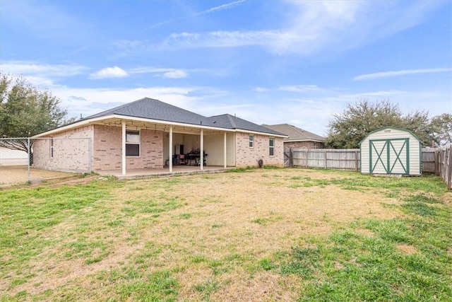 back of house featuring a lawn, a patio area, a shed, a fenced backyard, and an outdoor structure