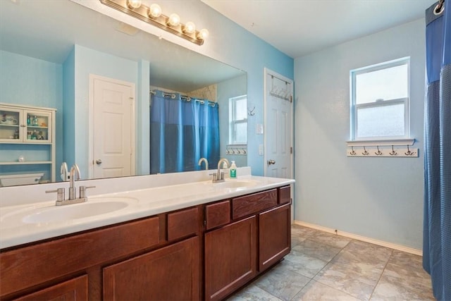 full bath with a healthy amount of sunlight, a sink, and double vanity