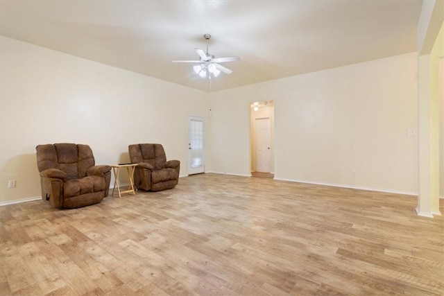 sitting room with light wood-type flooring, baseboards, and a ceiling fan