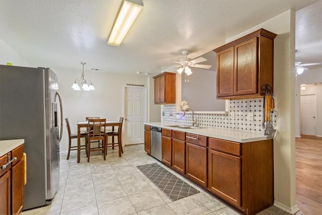 kitchen with decorative backsplash, brown cabinetry, appliances with stainless steel finishes, light countertops, and a sink