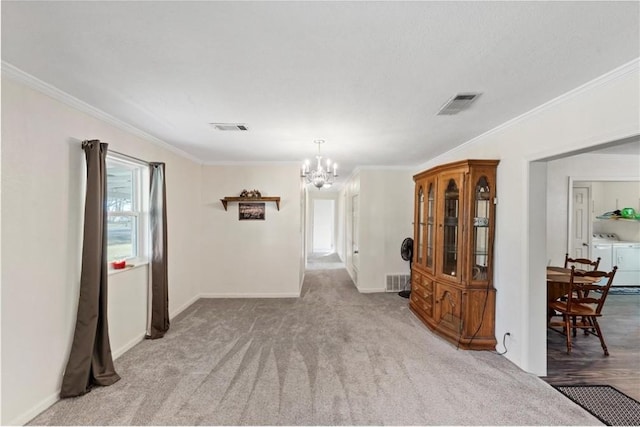 empty room featuring light carpet, an inviting chandelier, washer and dryer, and ornamental molding