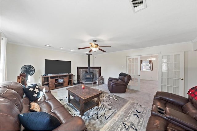 living room featuring a wood stove, light carpet, french doors, ceiling fan, and ornamental molding