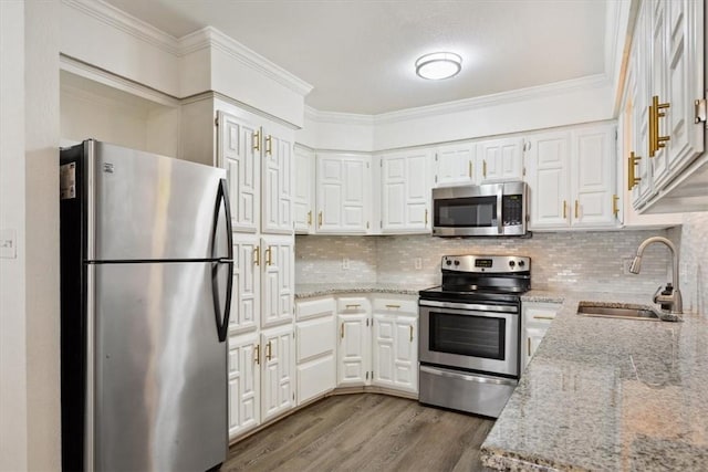 kitchen with white cabinetry, light stone countertops, sink, hardwood / wood-style floors, and appliances with stainless steel finishes