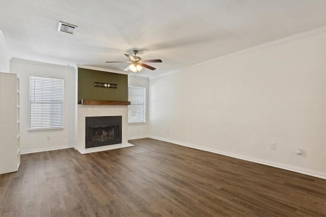 unfurnished living room featuring dark hardwood / wood-style floors, ceiling fan, crown molding, and a tiled fireplace